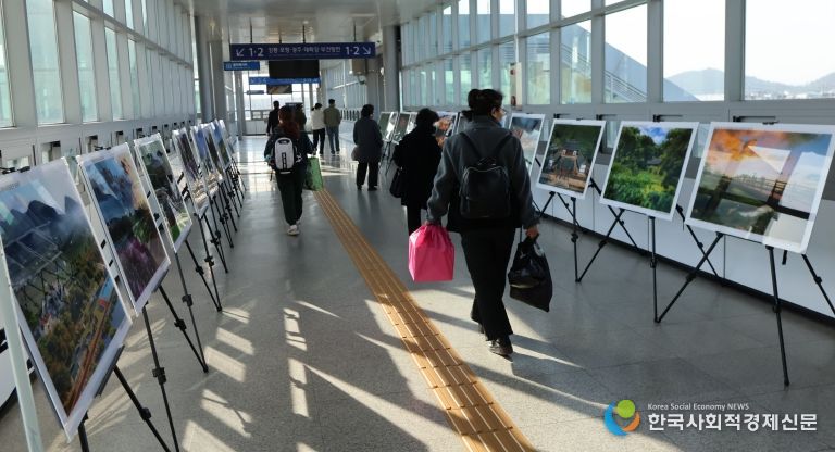 영천역 승강장 입출구 통로에 전시된 제17회 영천관광 전국사진공모전 입상작품을 철도 이용객들이 관람하고 있다.